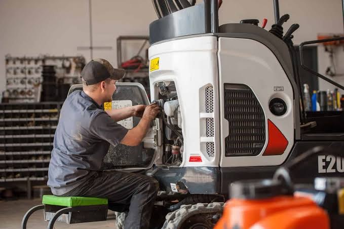 Mechanik Bujak Maszyny przy minikoparce Bobcat w warsztacie